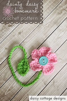 a crocheted flower with a blue button on the center sits on a wooden surface