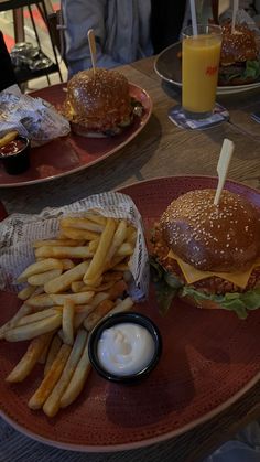 two plates with burgers and french fries on them