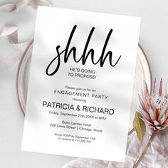 a white card with the word shhl on it next to some flowers and ribbons