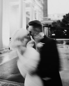 a bride and groom are kissing in front of the white columns at their wedding reception