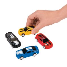 three toy cars being held in the air by a person's hand on a white background