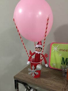 an elf is holding a pink balloon on top of a table