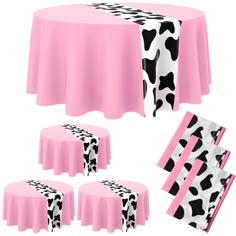 a pink table cloth with black and white cow print on it, along with matching napkins