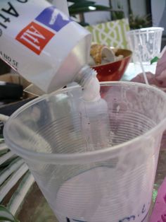 a plastic cup filled with milk being poured into the container and sitting on top of a table