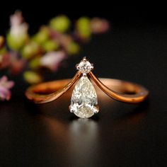 an engagement ring with a pear shaped diamond in the center and a flower behind it