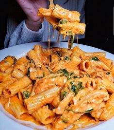 a person is eating pasta with cheese and spinach