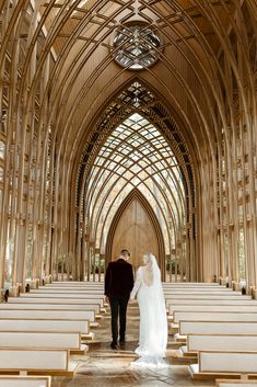 a bride and groom walking down the aisle of a large church with wooden pews