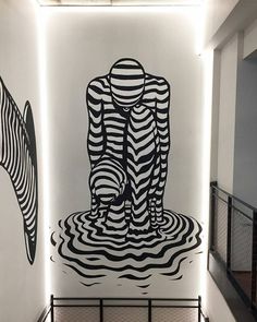 two zebras are sitting on the floor in front of a wall with black and white artwork