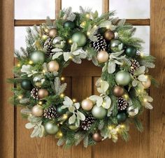 a christmas wreath on a door with pine cones and greenery hanging from the front