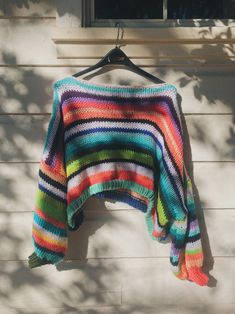 a multicolored sweater hanging on a clothes hanger next to a white wall