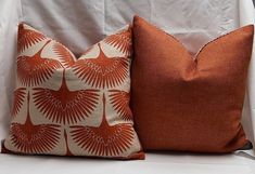 two orange pillows sitting on top of a white couch