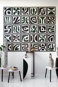 an abstract art work hangs on the wall in a white room with black and white furniture