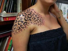 a woman with a leopard print on her arm and chest is standing in front of a bookshelf