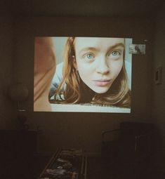 a woman's face is projected on a screen in a dark room with other items