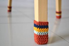 a pair of wooden legs with multicolored knitted socks on them sitting on the floor