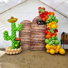 some balloons are arranged in the shape of cactuses and other items on display under a tent