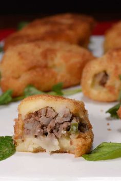 some food on a white plate with green leafy leaves around it and one bite taken out