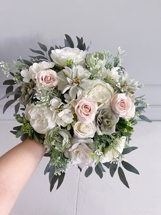 a bouquet of white and pink flowers is being held by a person's hand