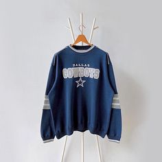 a sweatshirt hanging on a clothes rack with the word cowboys printed on it and an orange hanger