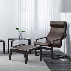 a chair and table in a room with white curtains on the window sill, two end tables next to each other