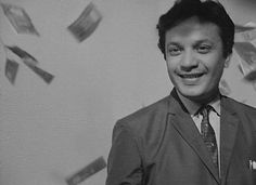 a black and white photo of a man in a suit with money flying around him