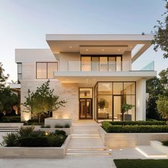 a modern house with white walls and landscaping in front of the entrance to the home