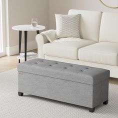 a living room with a white couch and gray storage bench in front of the sofa