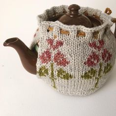 a knitted teapot cover with flowers on it