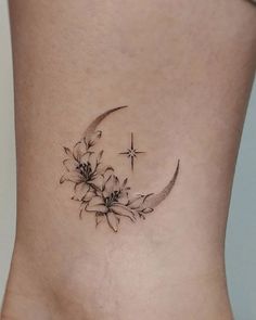 a woman's lower back tattoo with flowers and a crescent moon on the side