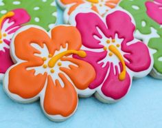 decorated cookies with flowers on them sitting on a blue tableclothed surface, ready to be eaten