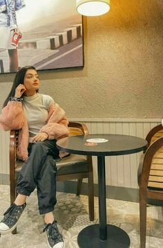 a woman sitting at a table talking on the phone