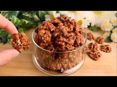 someone is holding up some nuts in a glass bowl on a wooden table next to flowers