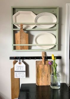 a shelf with plates and cutting boards on it next to a vase filled with flowers