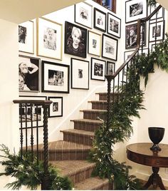 a staircase decorated with christmas greenery and framed pictures on the wall above it, along with potted plants