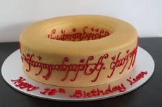 a yellow birthday cake with red writing on the top and bottom is sitting on a white plate