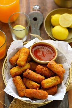 there are some fried food on the plate and orange juice in the glass next to it