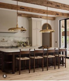 a large kitchen with wooden floors and white counter tops, gold pendant lights hanging from the ceiling