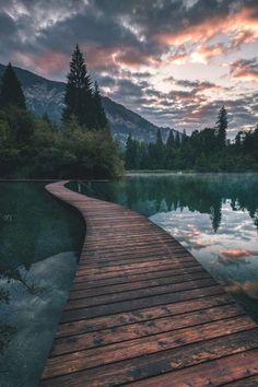 a wooden dock sitting next to a body of water under a sky filled with clouds