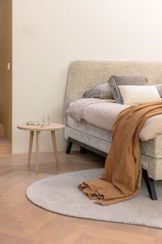 a bed sitting on top of a wooden floor next to a table