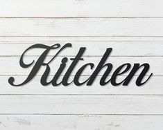 the word kitchen written in black on a white wood background