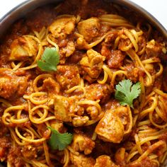 a pan filled with pasta and meat covered in sauce, garnished with cilantro