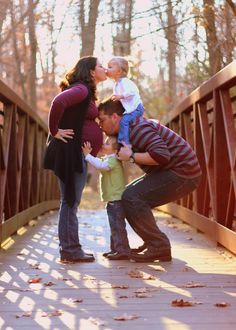 a man, woman and child kissing on a bridge