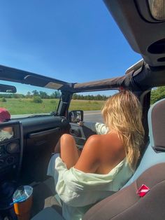 a woman sitting in the driver's seat of a car looking out the window