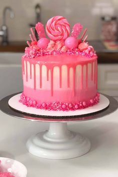 a cake with pink icing and lollipops on top sitting on a plate