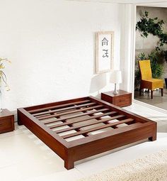 a bedroom with white walls and wooden furniture in the room, including a bed frame