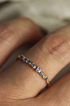 This gorgeous hand-sculpted ring features 7 sparkling blue sapphires set with the daintiest of prongs in an ocean inspired texture. Delicate and comfortable to wear, this solid gold sapphire ring would make the perfect feminine, oceanic wedding band or everyday ring to add to your stack! Details:- Available in 10k yellow or white gold, or 14k, yellow, rose or white gold- Responsibly sourced, natural blue sapphires (.09 total carat weight)- Widest point at the top is approx 1.8mm, bottom of the b Safire Wedding Band, Gold Sapphire Wedding Band, Wedding Bands With Sapphires, Dainty Birthstone Ring, Wedding Band With Colored Stones, Blue And Gold Rings, Wedding Band Colored Stones, Edwardian Wedding Band, Saphire Engament Ring Gold Band