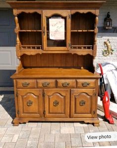 an old wooden china cabinet sitting on top of a brick floor