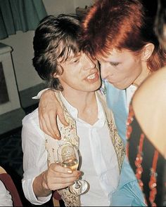 two people hugging each other while holding wine glasses