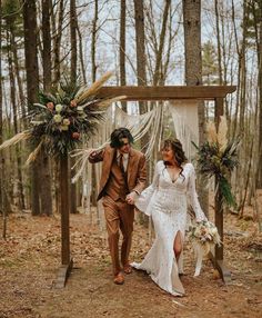 a bride and groom are walking through the woods holding each other's hands as they walk down the aisle