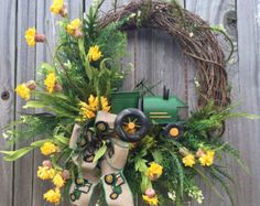 a wreath with yellow flowers and a tractor on it is hung on a fence outside